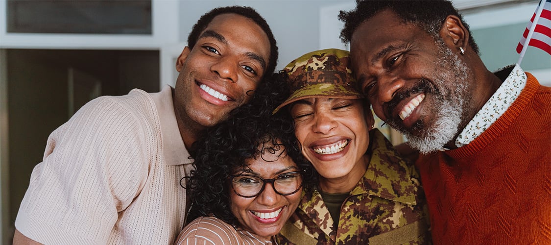 A woman in military clothing smiling with husband and parents.