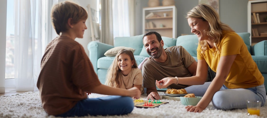 Family sitting on living room floor playing a board game
